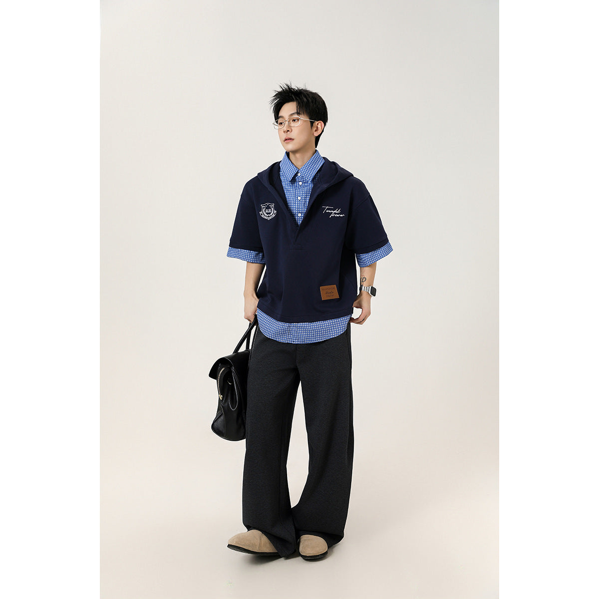 Model wearing a navy short-sleeve hooded pullover over a blue checked shirt.