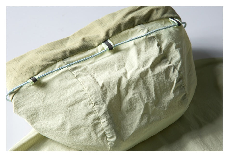 Close-up of a pale sage garment panel with a blue-and-white adjustable cord threaded along its edge.