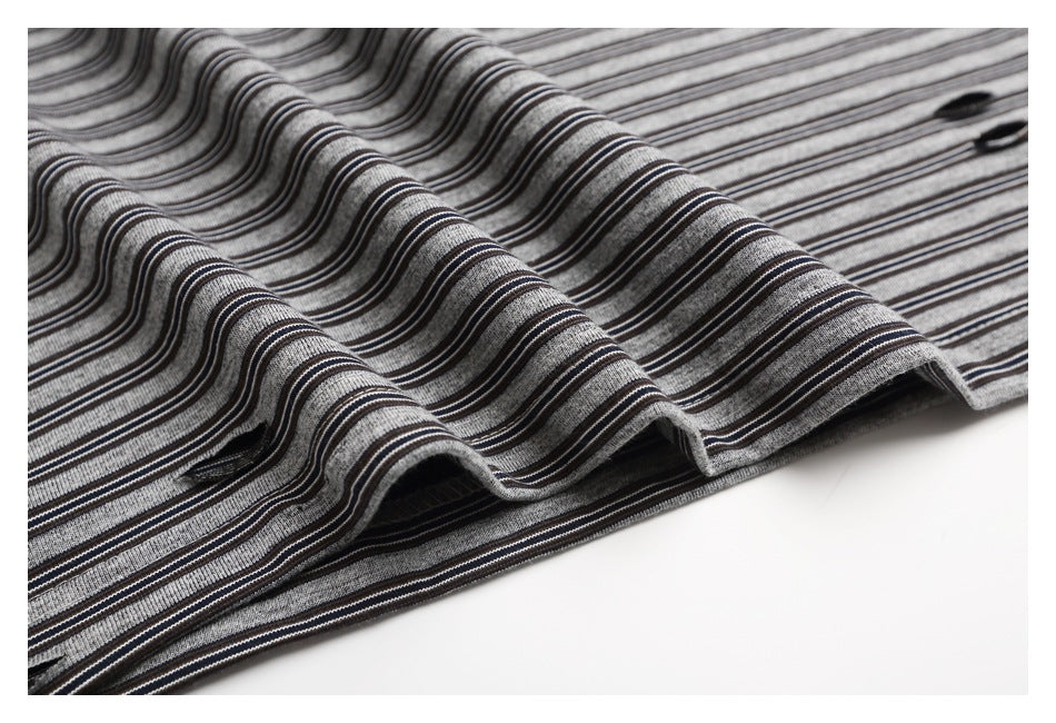 Close-up of the gray and black striped T-shirt fabric draped in folds, showing its stripe pattern.