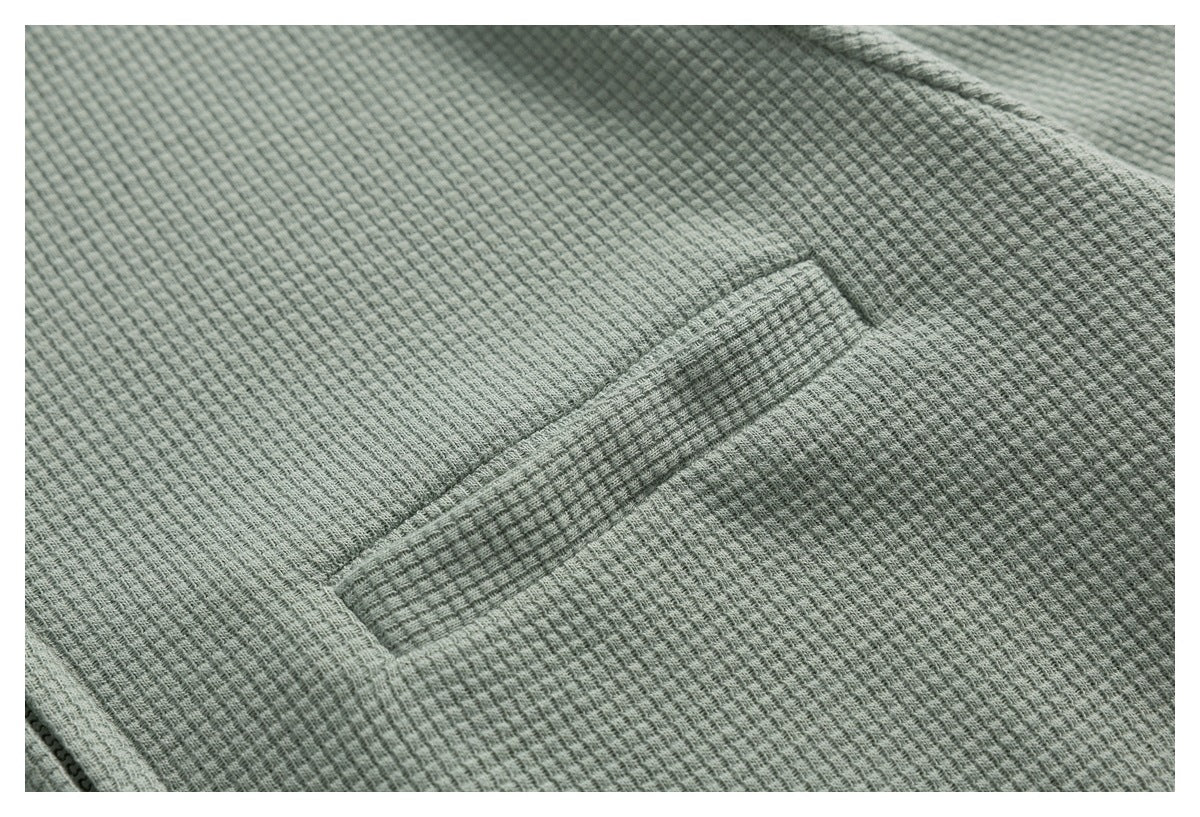 Close-up of a sage green textured top showing a narrow welt pocket.