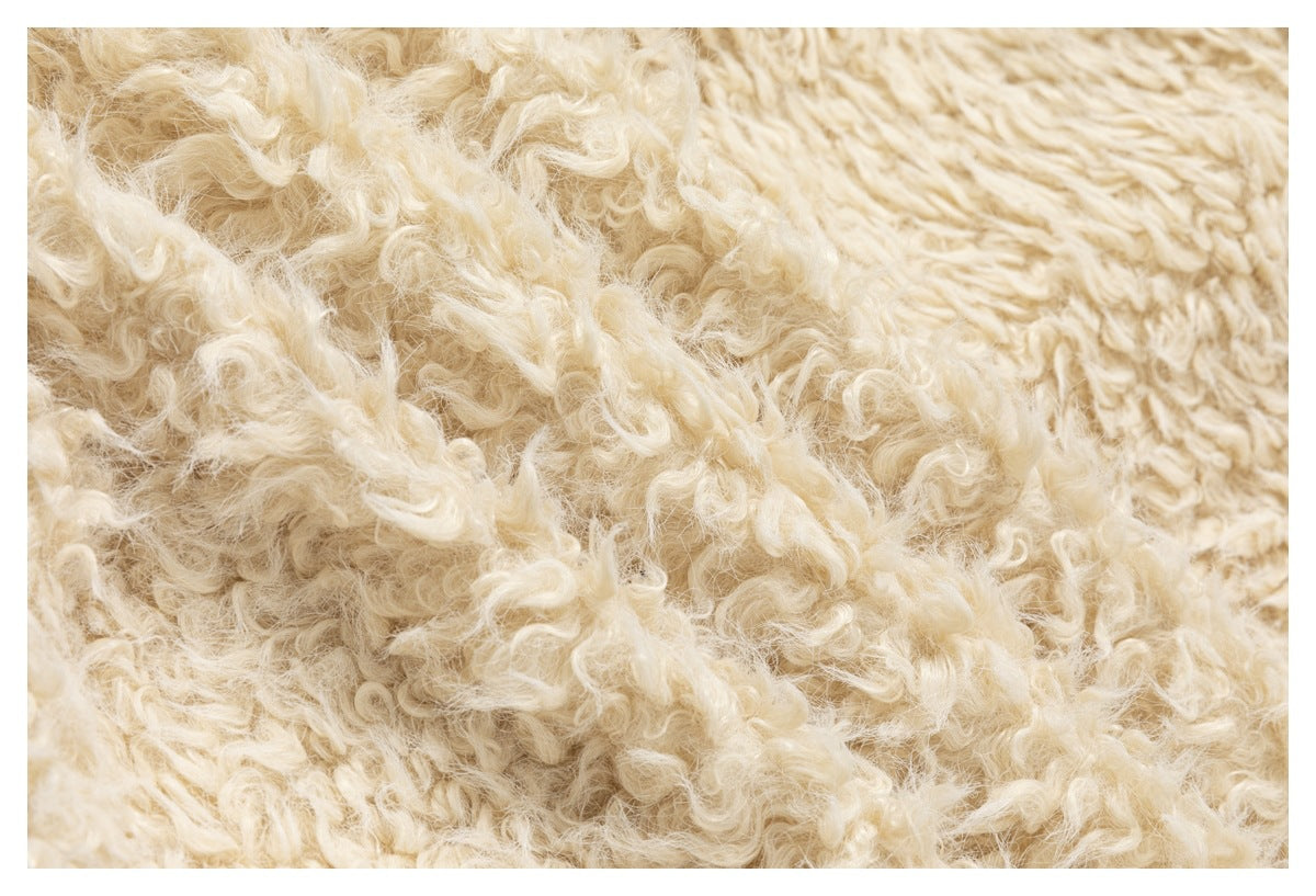 Close-up of the cream curly pile and beige cable-knit fabric.