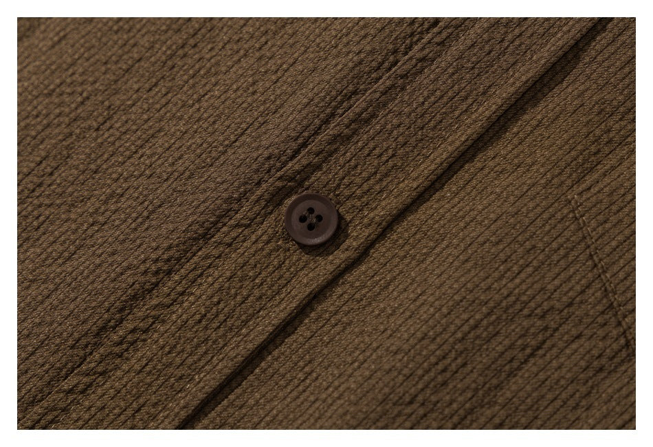 Close-up of a dark brown button and the shirt's fine textured fabric.