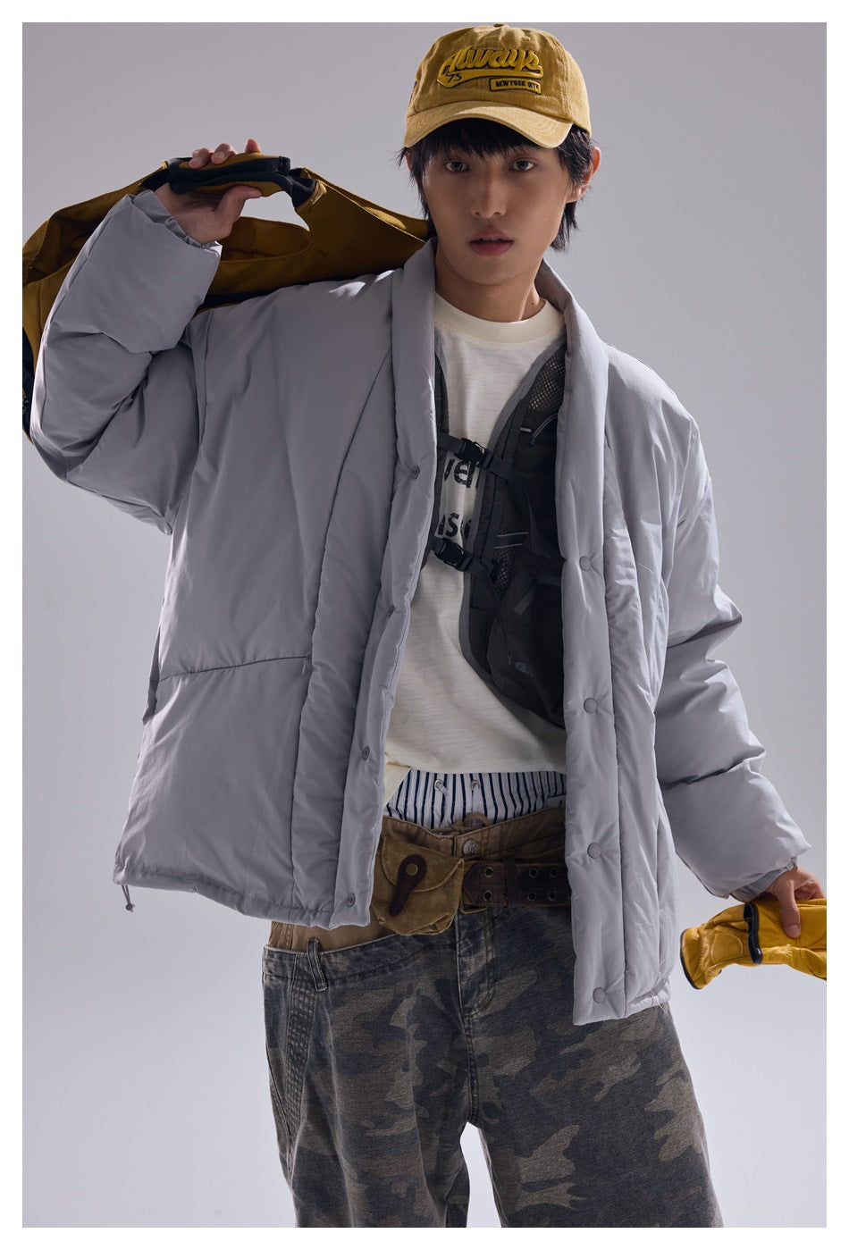 Front view of a model wearing a light gray oversized quilted jacket with snap buttons and large pockets.
