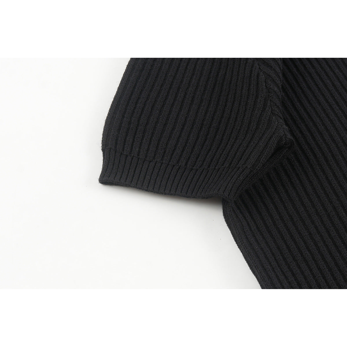 Close-up of the black ribbed sweater's short sleeve and ribbed cuff.