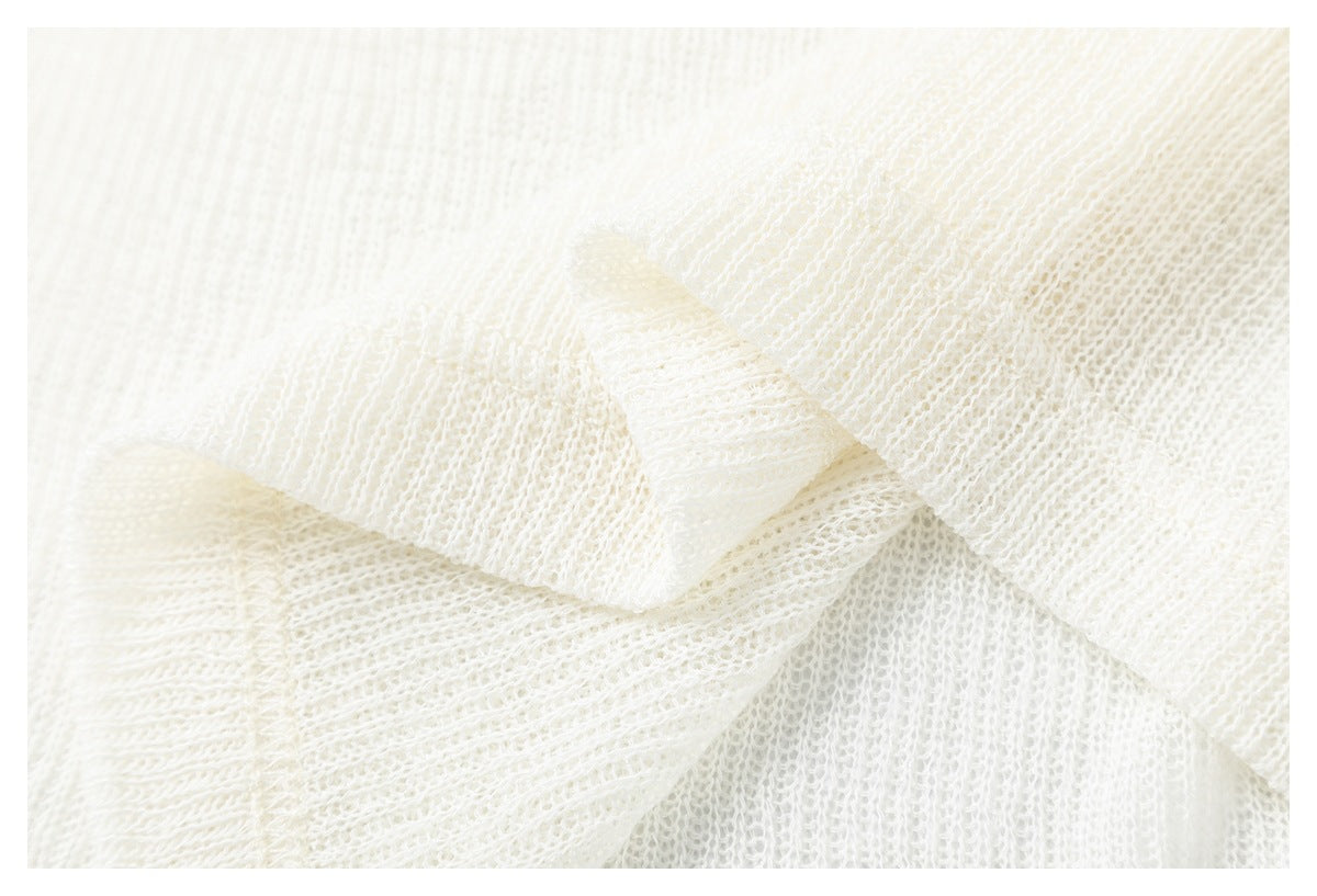 Macro view of the open, textured ivory knit fabric and overlapping folds.