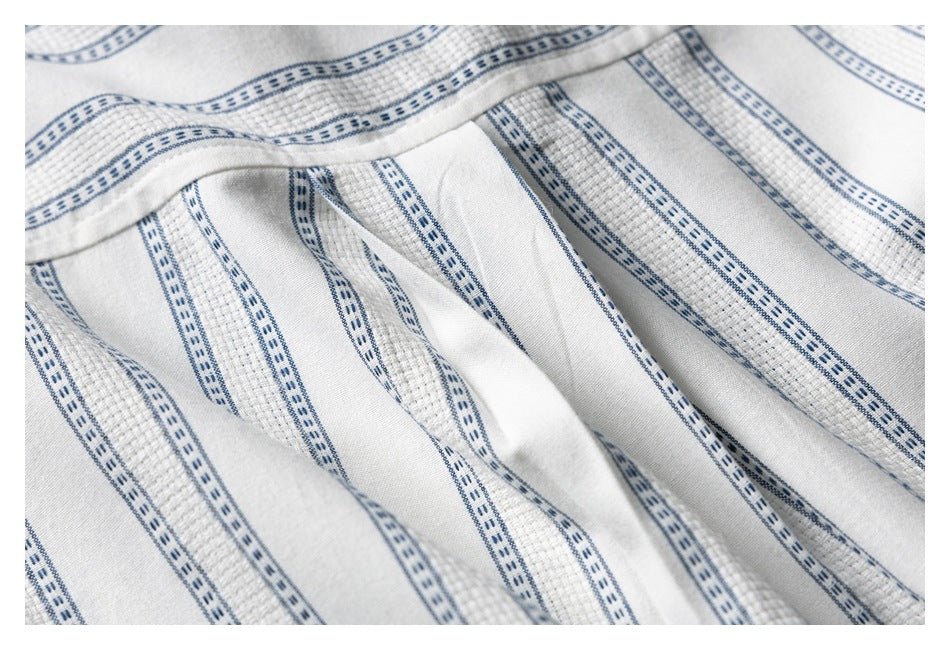 Close-up of a seam and folded fabric on a white shirt with narrow blue stripes.