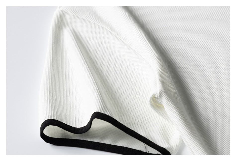 Close-up of white textured fabric with a black bound edge and a small stitched opening.
