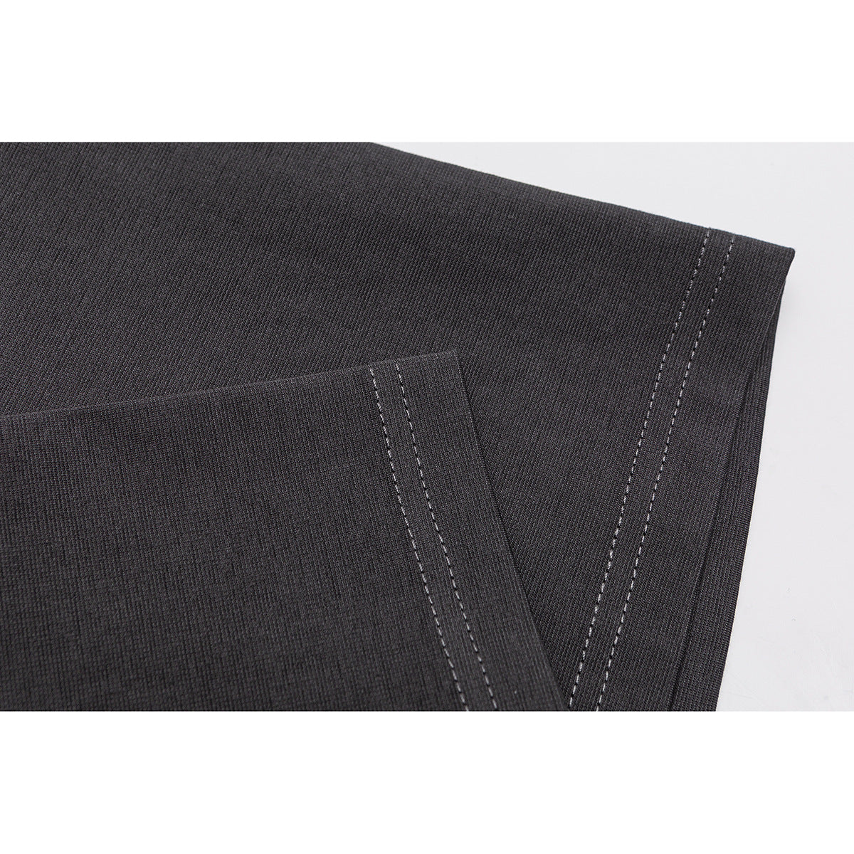 Close-up of dark charcoal fabric with parallel rows of light stitching along the garment edge.