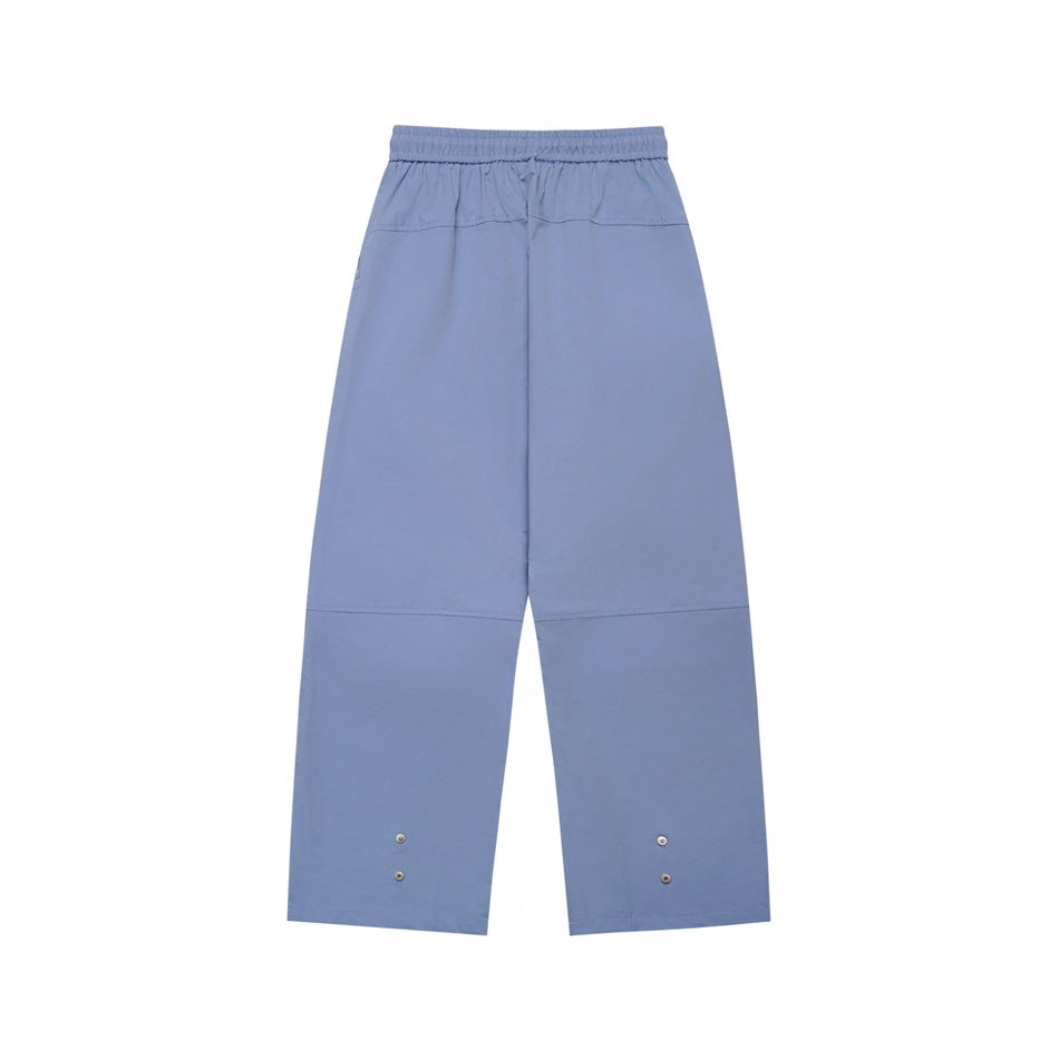Back view of light blue wide-leg pants with an elastic waistband and small snaps near the hems.