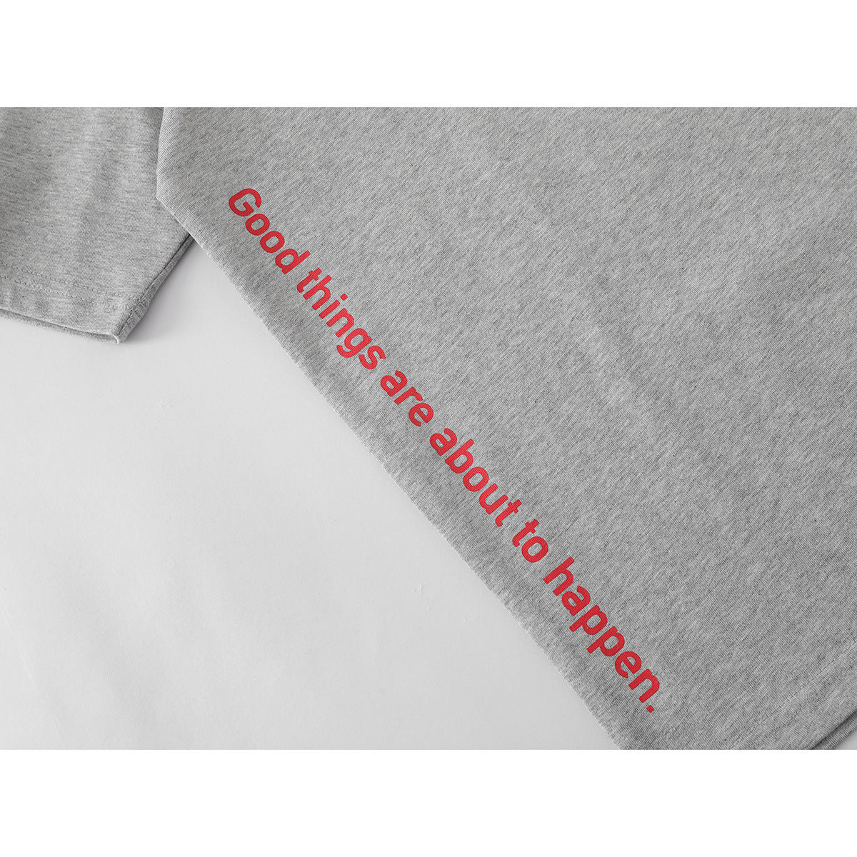 Close-up of a heather-gray T-shirt showing the red printed phrase “Good things are about to happen.”