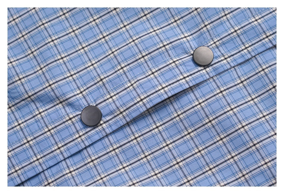Close-up of blue plaid shirt fabric and two dark buttons along the front placket.