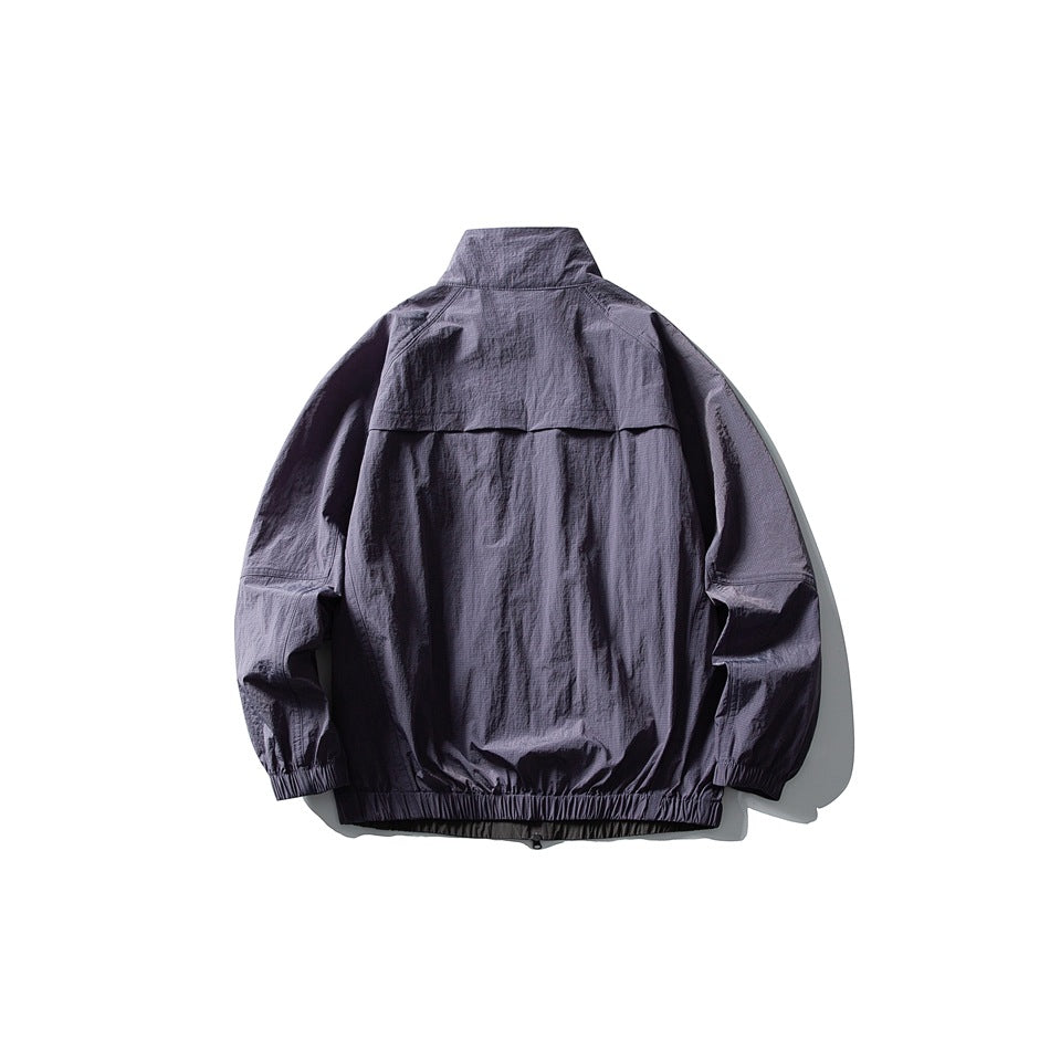 Back view of a muted purple-gray jacket with a high collar, back vent flap, and elastic cuffs and hem.
