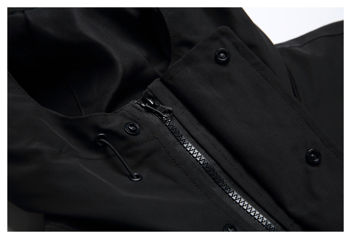 Close-up of a black garment's zipper, snap fasteners, and drawcord eyelets.