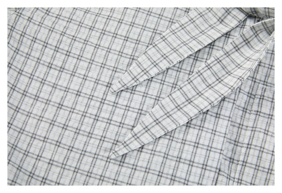 Close-up of the shirt's matching plaid tie detail laid over white and gray plaid fabric.