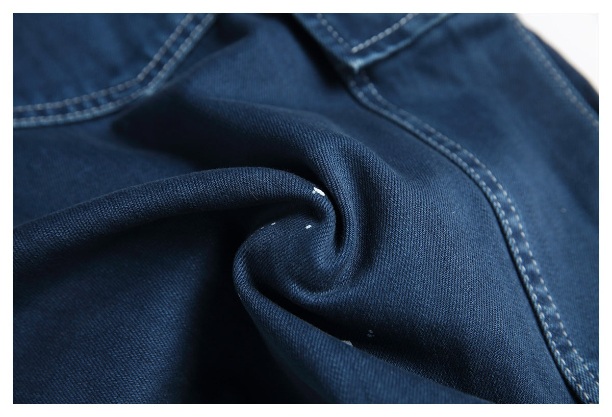 Close-up of dark blue denim folded into a soft twist, with visible diagonal weave and pale contrast stitching.