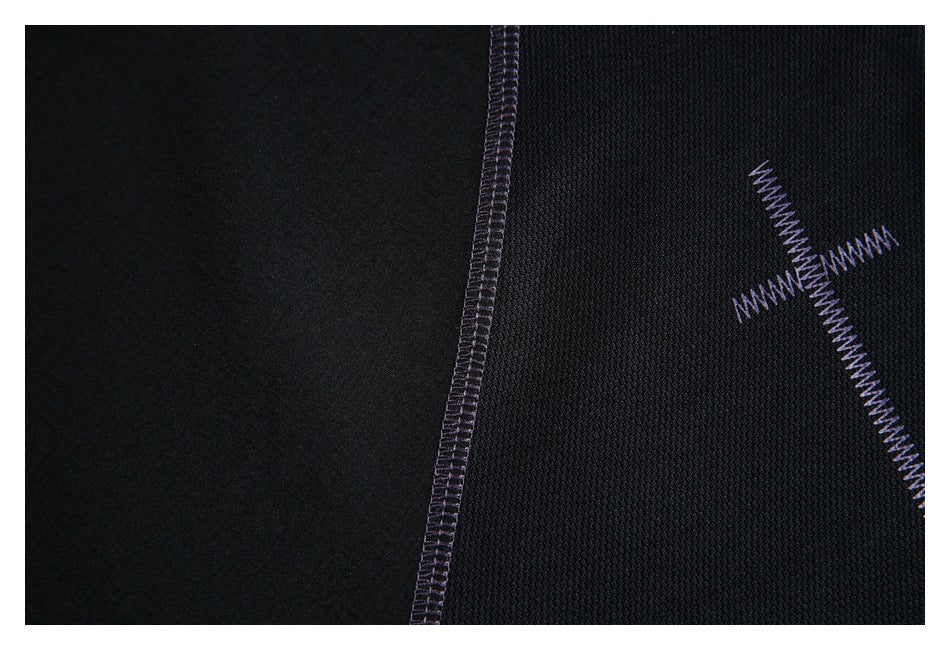 Close-up of black fabric panels with a purple overlock seam and cross-shaped zigzag stitching.