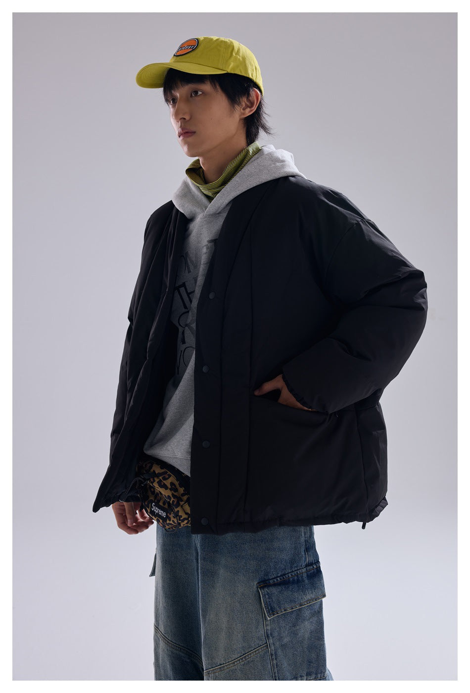 Model wearing an oversized black snap-front quilted jacket over a gray hoodie.