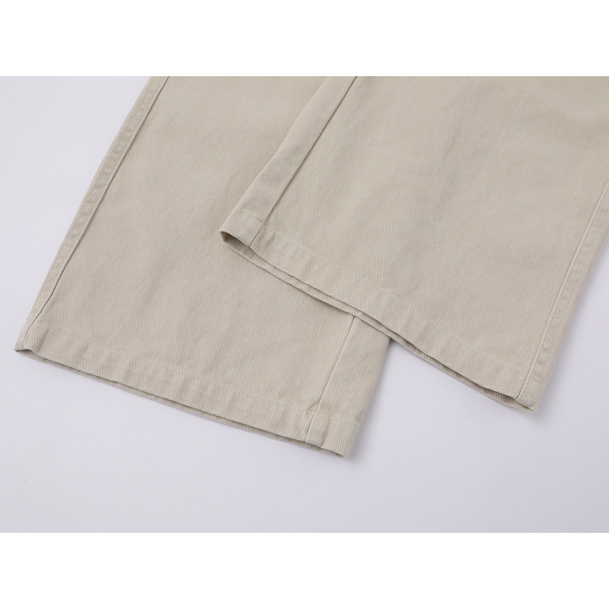 Close-up of the hems of beige wide-leg trousers, showing the stitching and leg openings.