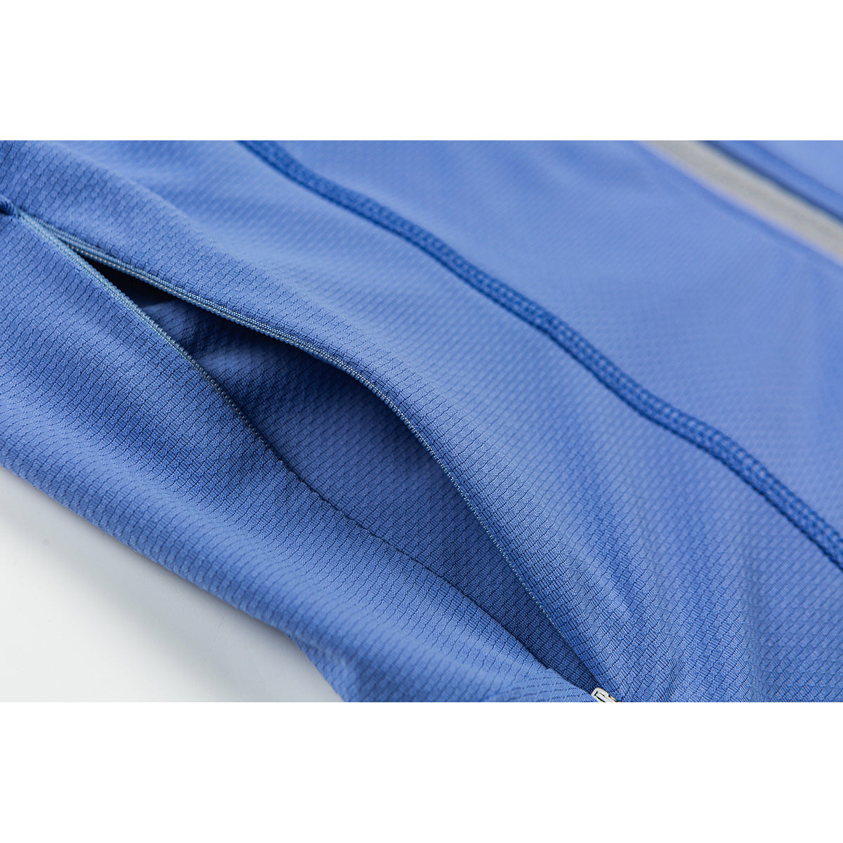 Close-up of a pocket opening and stitched seam on the blue jacket.