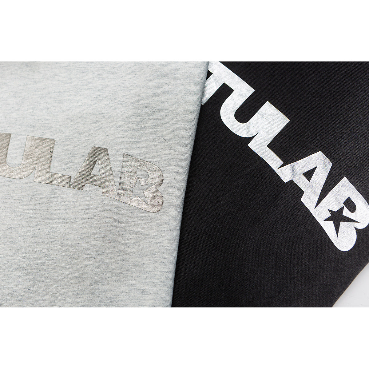 Close-up of gray and black T-shirt fabric with large contrasting lettering and star graphics.