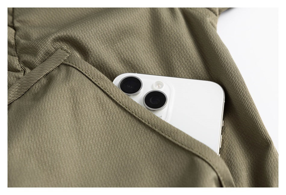 Close-up of an olive garment pocket holding a white smartphone.