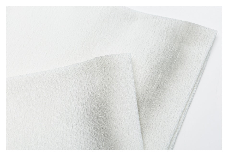 Close-up of white garment fabric with a folded edge and visible textured weave.