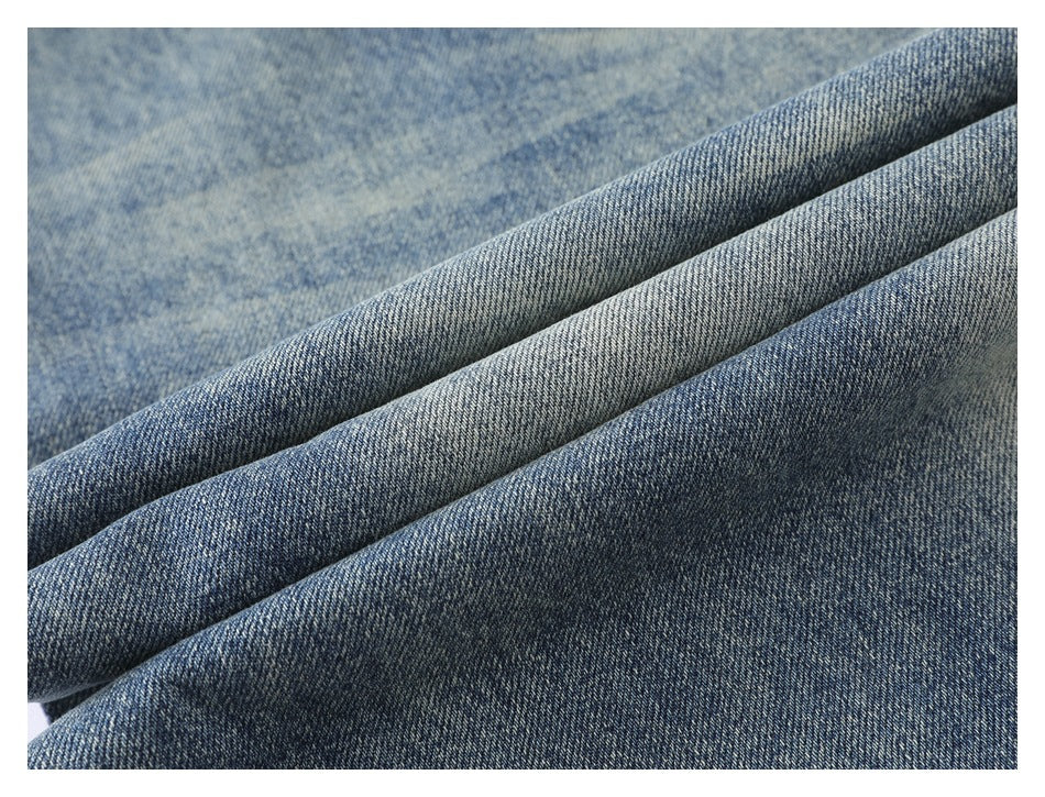 Macro view of blue denim fabric draped in folds, showing its faded wash and weave.