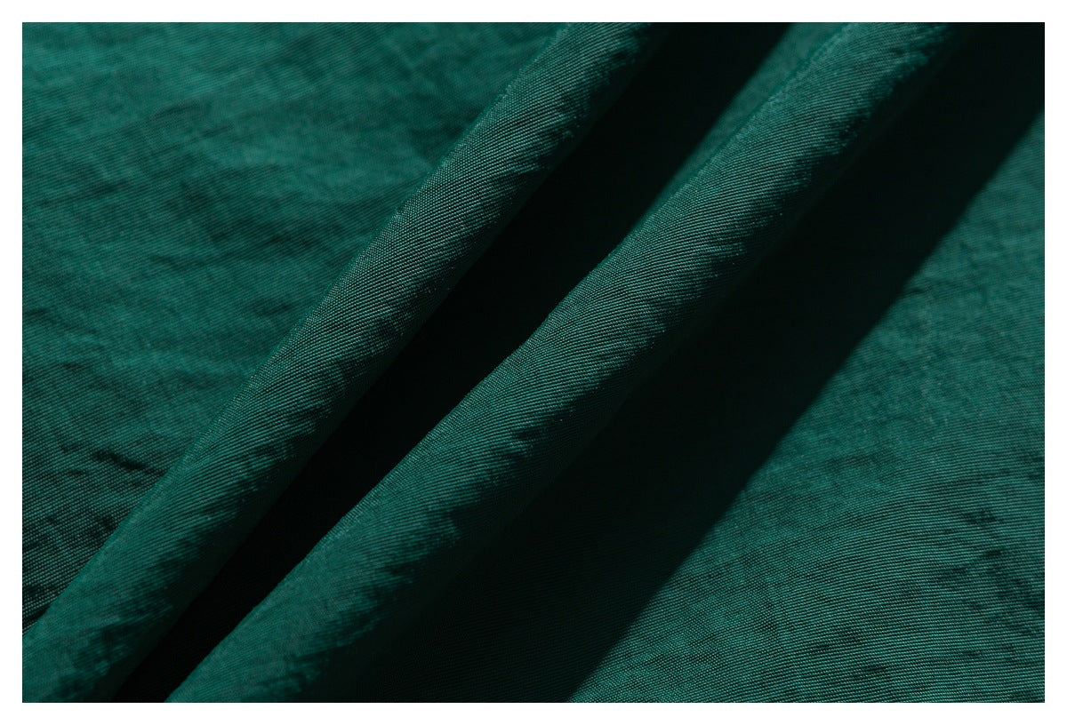 Macro view of teal-green fabric folds showing its surface texture and drape.