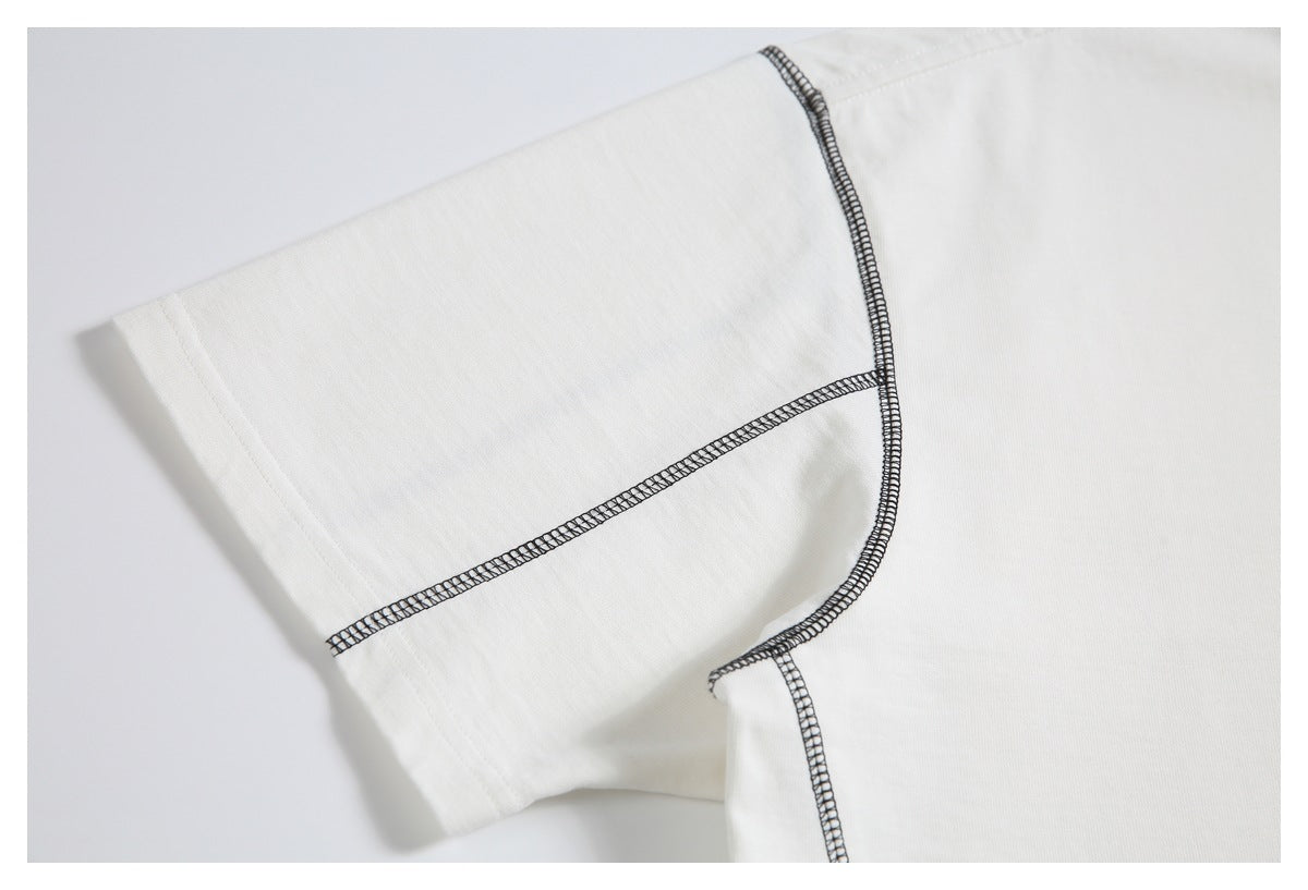 Close-up of an off-white T-shirt sleeve with black contrast overlock stitching along the seams.