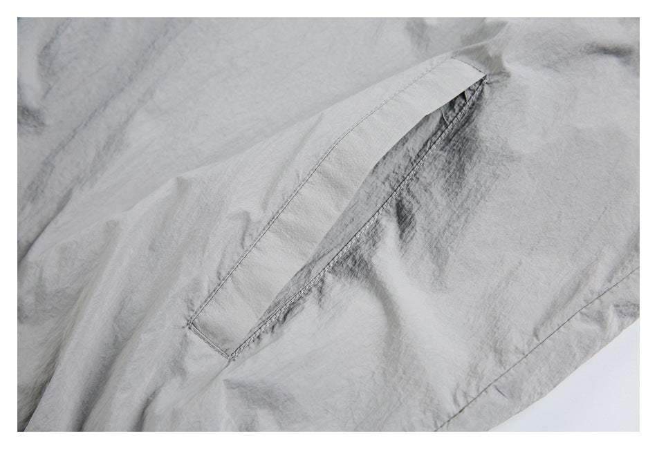 Close-up of a slanted welt pocket on a light gray jacket.
