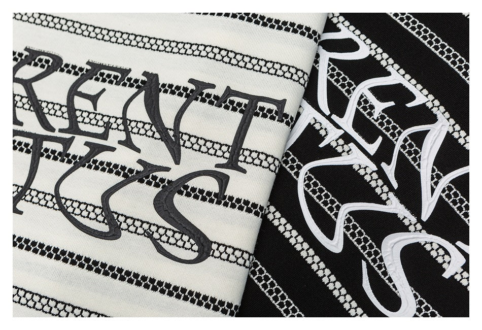 Close-up of ivory and black striped T-shirts with large contrasting lettering across the fronts.
