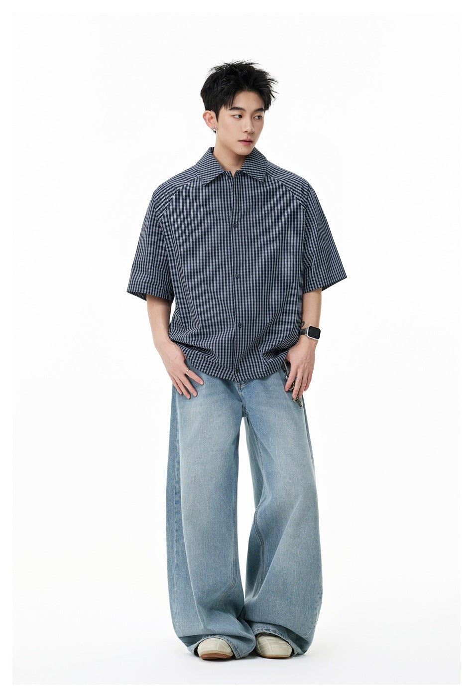 Full-length view of a model in a dark navy short-sleeve plaid shirt and wide-leg light blue jeans.
