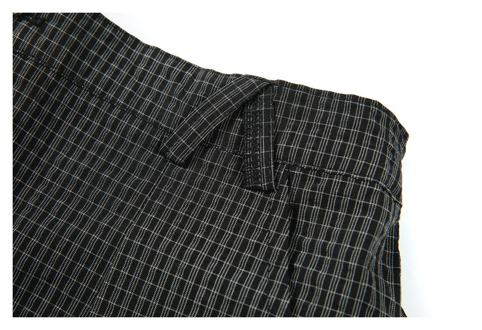 Close-up of black trousers with a fine gray windowpane check, showing the waistband and a belt loop.