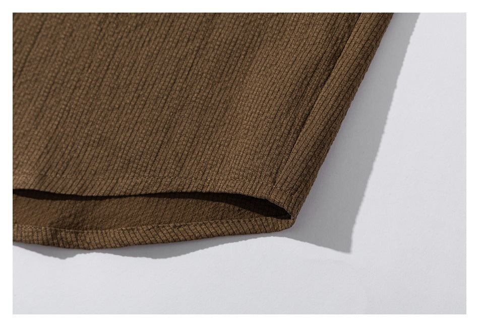 Close-up of the brown shirt's curved hem and textured fabric.
