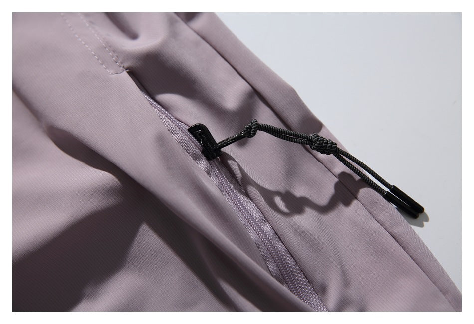 Close-up of a muted mauve garment with a zipper and black cord-and-toggle detail.