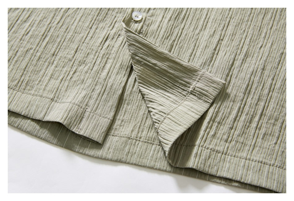 Close-up of the muted olive-gray shirt's button placket and overlapping striped fabric panels.