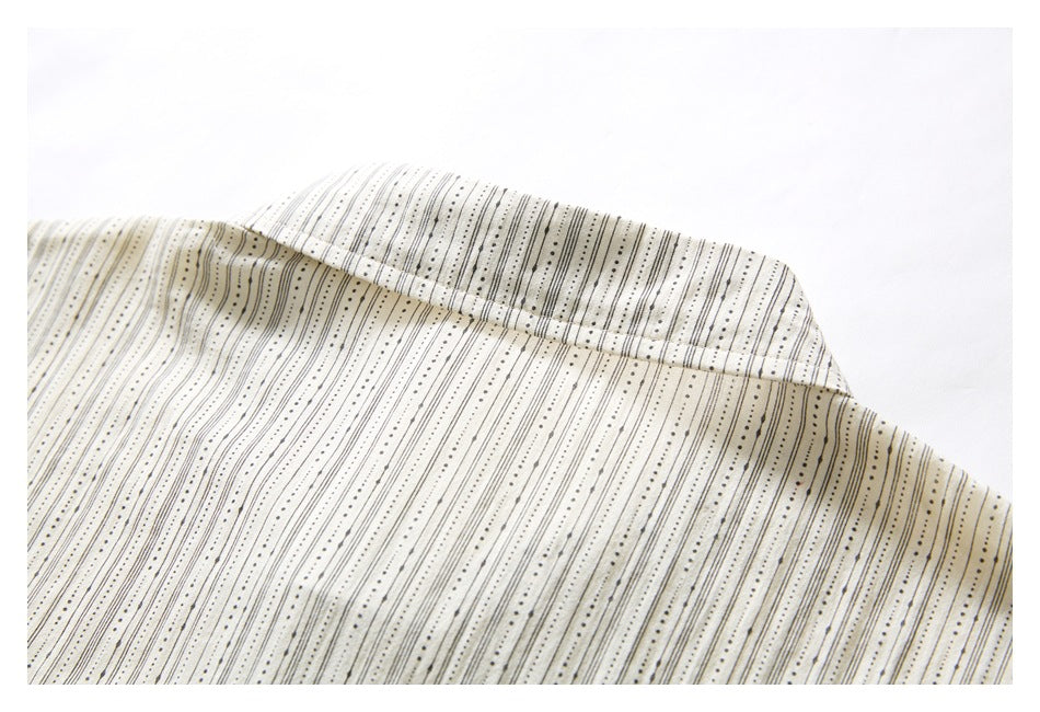 Close-up of an ivory garment collar with fine black dotted and solid vertical stripes.