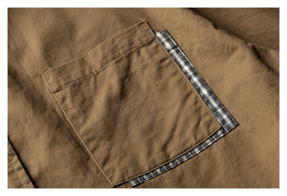 Close-up of a brown shirt pocket edged with dark plaid trim.
