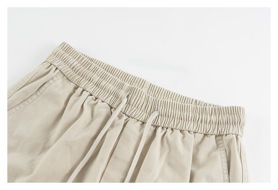 Close-up of beige shorts with a gathered elastic waistband and matching drawstrings.