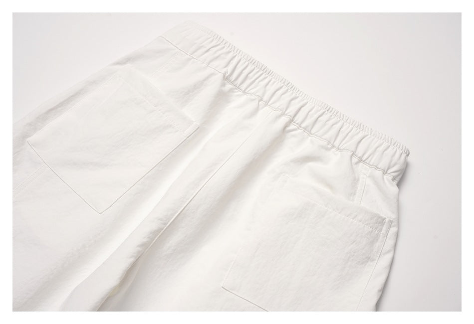Close-up of off-white pants with an elastic waistband and two large back patch pockets.