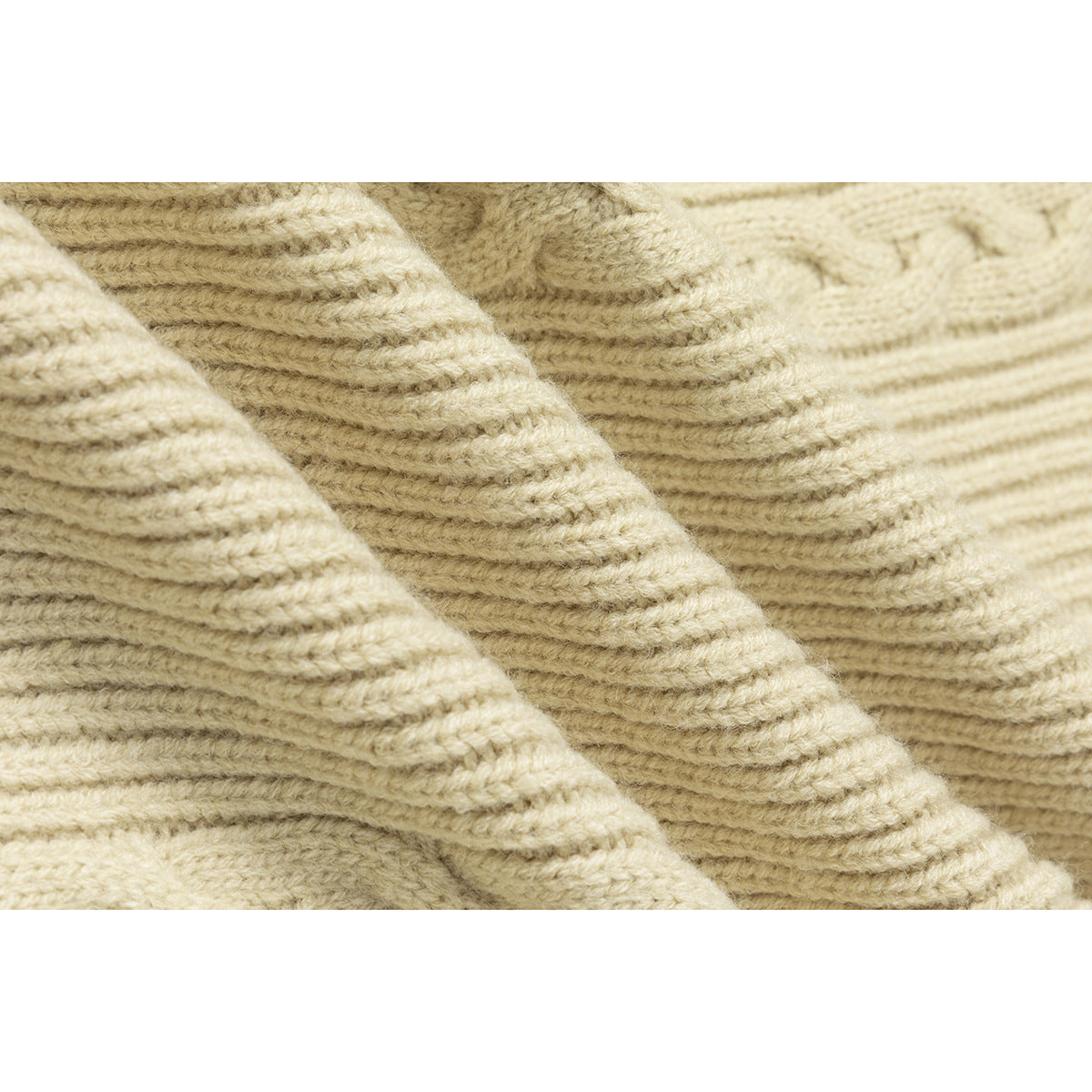 Macro view of the ivory sweater's raised ribbed and cable-knit texture.
