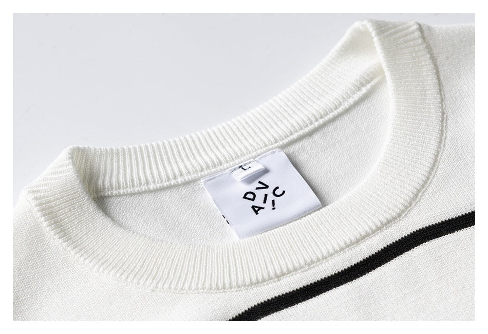 Close-up of an ivory knit top's ribbed crew neck, sewn-in label, and black stripe.