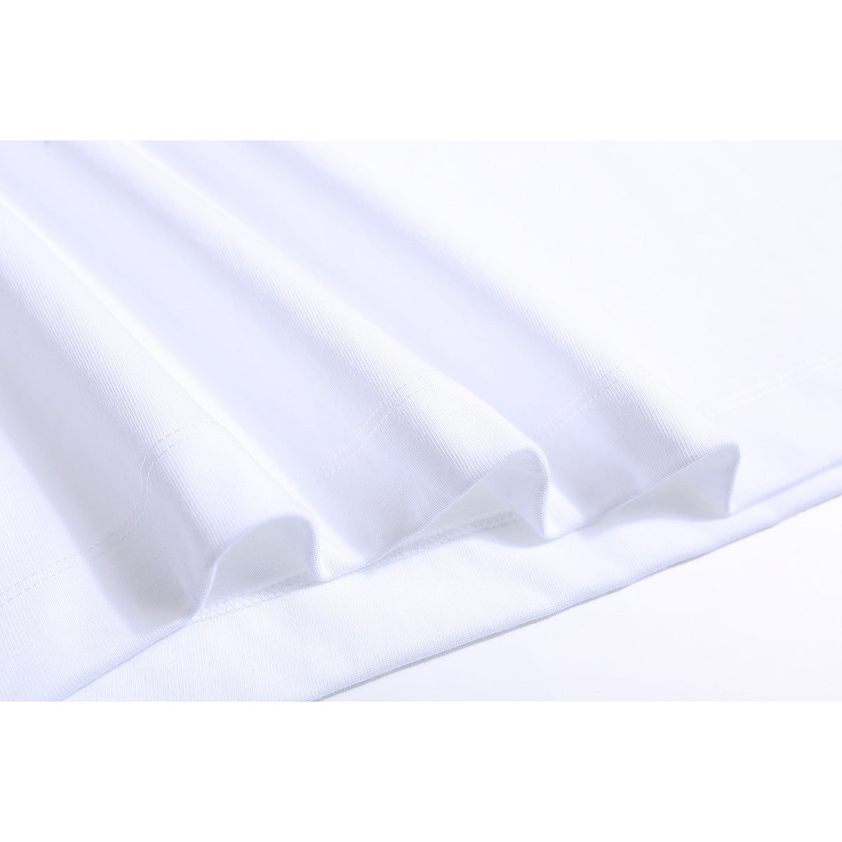 Close-up of the stitched hem and fabric folds of a white T-shirt.