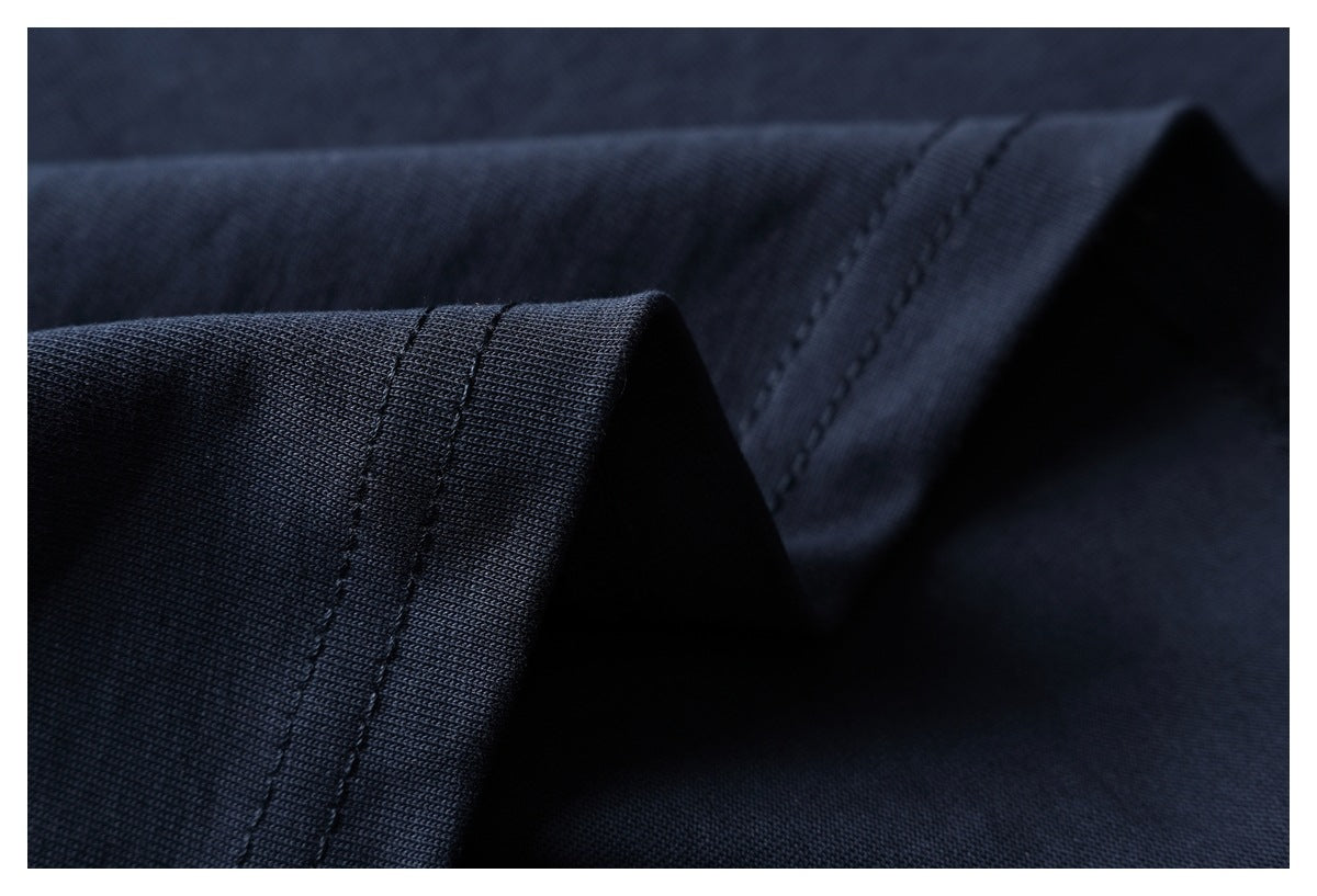 Close-up of dark navy fabric folded to show a stitched edge and seam.
