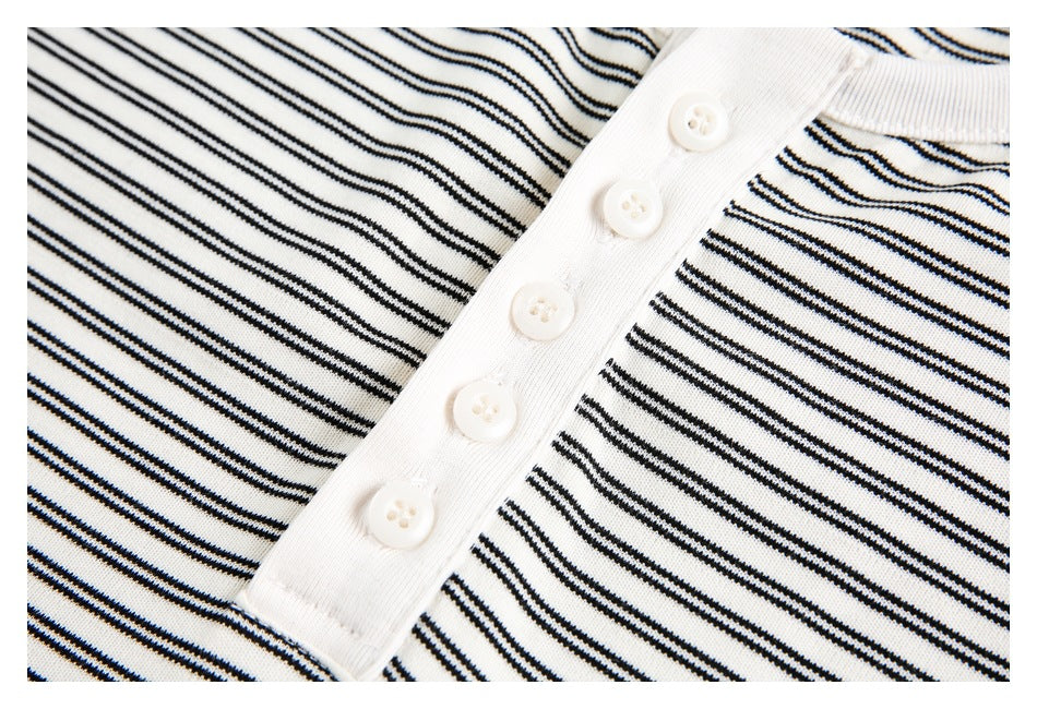 Close-up of the white five-button placket on a white shirt with thin black stripes.