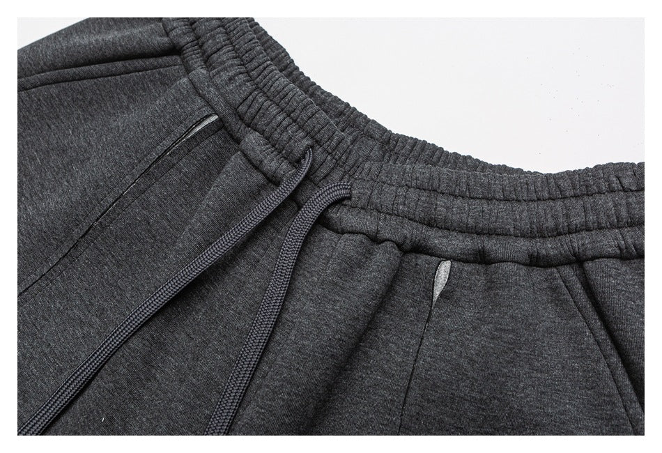 Close-up of charcoal gray jogger pants showing the elastic waistband, drawstring, and zippered pocket.