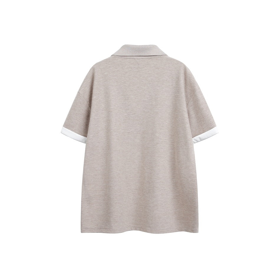Back view of a taupe short-sleeve collared shirt with white sleeve cuffs.