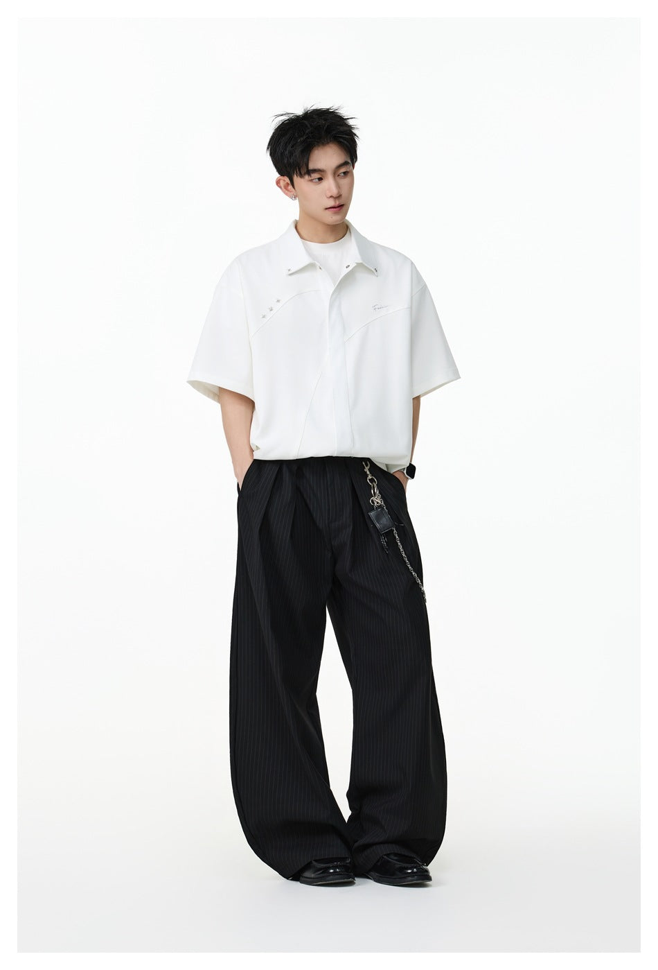 Full-length view of a model wearing an oversized white short-sleeve button-up shirt and black pinstripe trousers.
