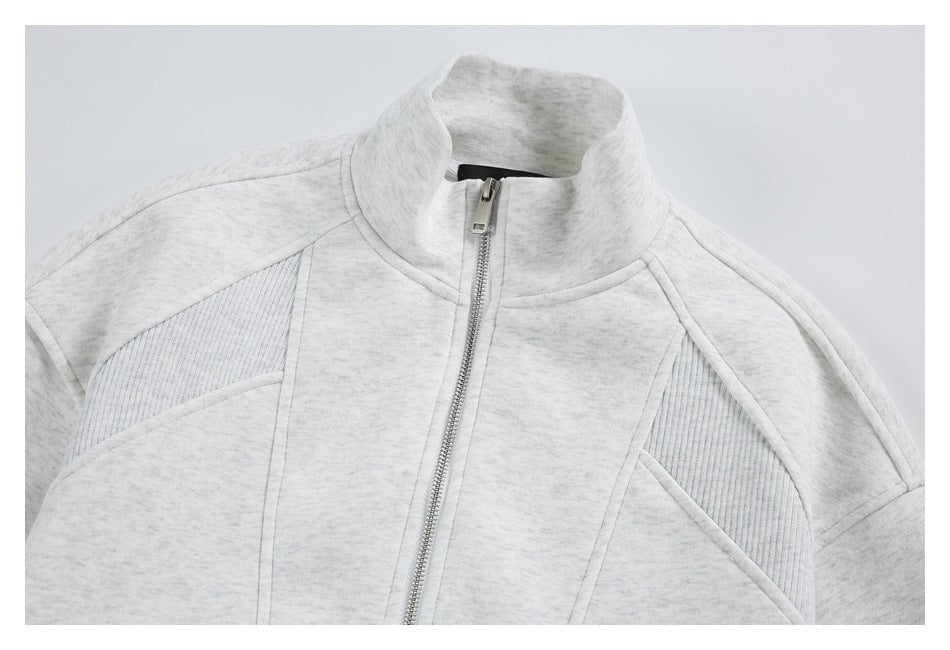 Close-up of a light gray marled zip-up jacket showing its tall stand collar, front zipper, and curved panel seams.