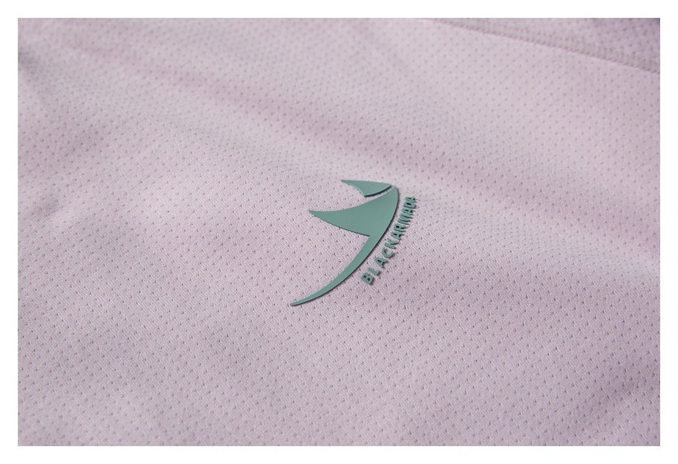 Close-up of pale pink perforated garment fabric with a raised mint-green emblem and lettering.